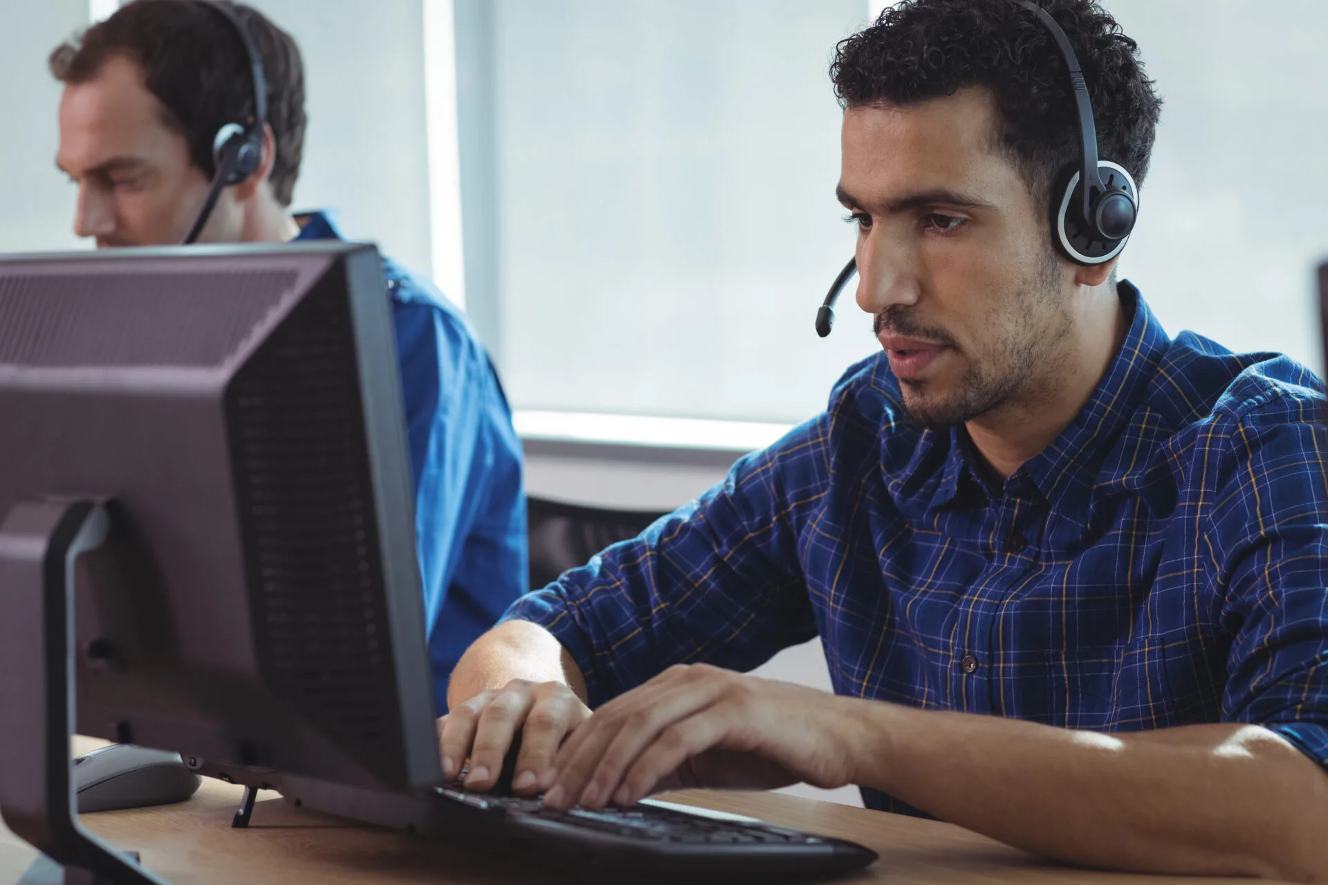 Call centre agents with headsets working at computers